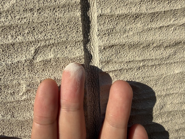 縦樋の横にあるコーキングが白っぽく粉をふいている様子