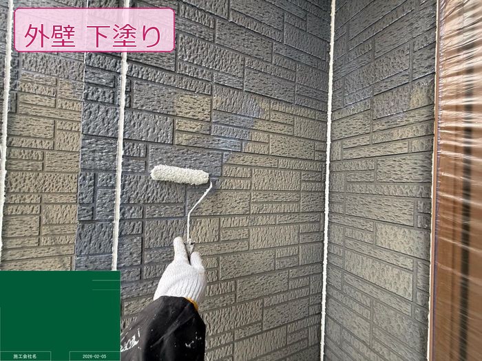 ローラーで外壁サイディングに下塗り材を塗布している様子