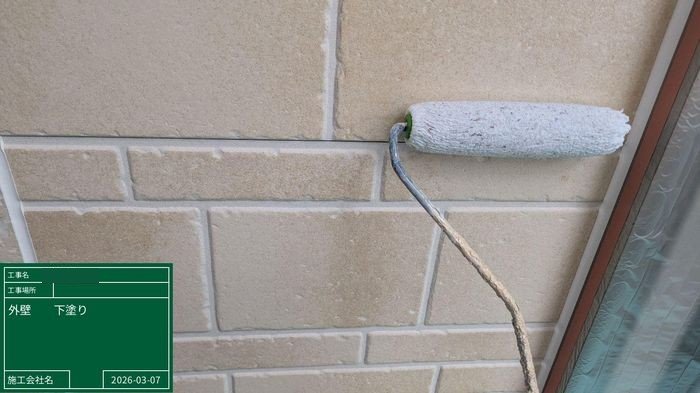 八尾市 外壁タイル調サイディングにローラーで下塗りを施工している様子