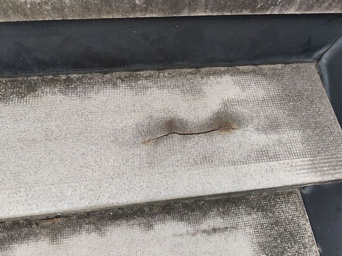 平野区喜連のアパート スレート屋根材に走るクラック（ひび割れ）と周囲に広がる雨染みのクローズアップ