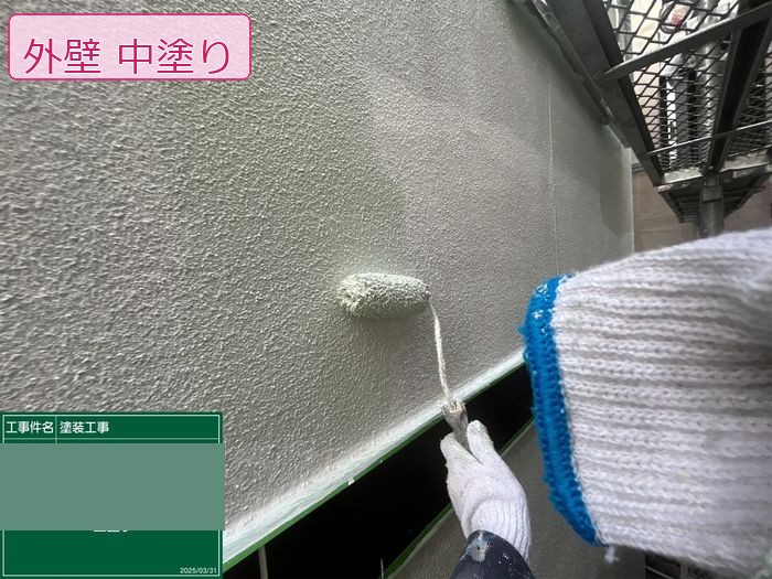 八尾市久宝寺のM様邸 中塗り施工中 ローラーで塗料を均一に塗り広げている様子