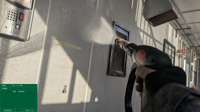 平野区喜連のアパート 共用廊下の外壁面をインターホン周辺まで丁寧に高圧洗浄している様子