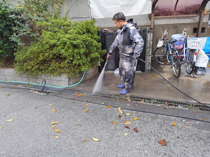 平野区喜連のアパート 駐車場の外構床面を高圧洗浄している様子 落ち葉が散らばる秋の現場