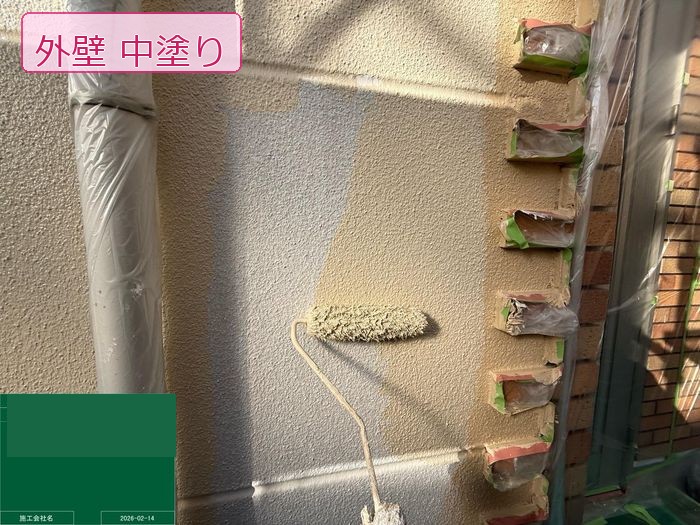 八尾市高安町 ALC外壁にベージュ系の中塗り塗料をローラーで施工している様子