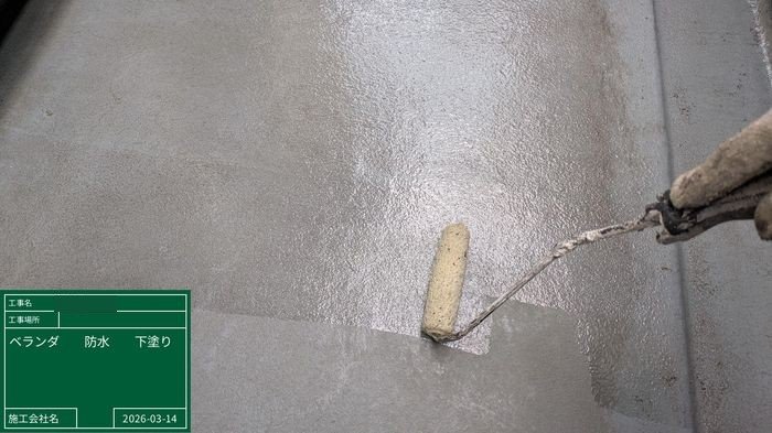 八尾市 ベランダ床面にローラーでプライマーを塗布している様子