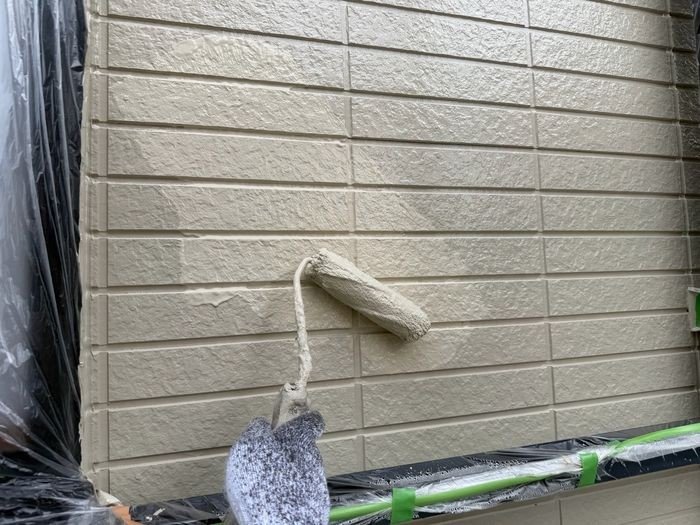 堺市東区N様邸 外壁の上塗り。仕上げ塗料をローラーで均一に塗布中