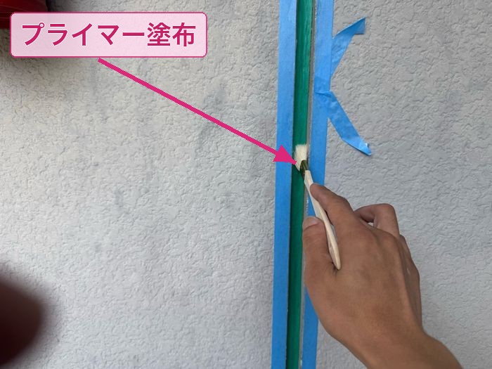平野区喜連のアパート シーリング打ち替え工事でプライマーを筆塗りしている職人の手元クローズアップ