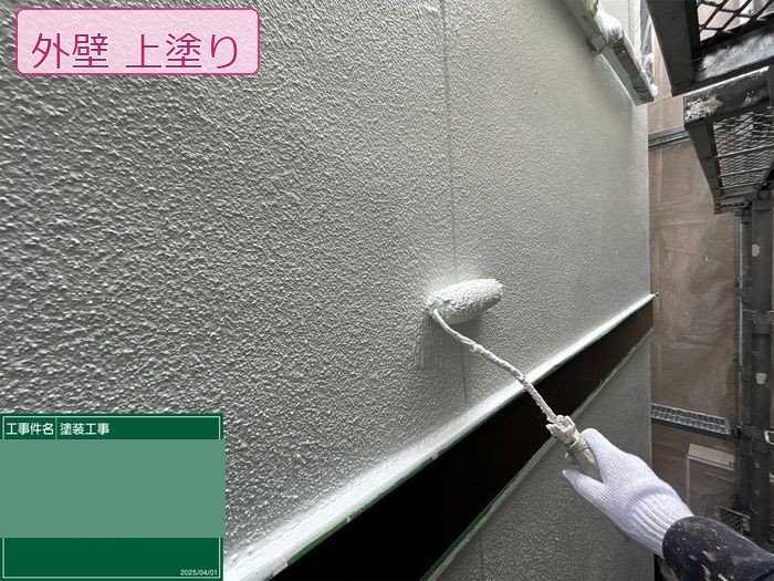 八尾市M様邸外壁の上塗り施工中。長柄ローラーで均一に塗布