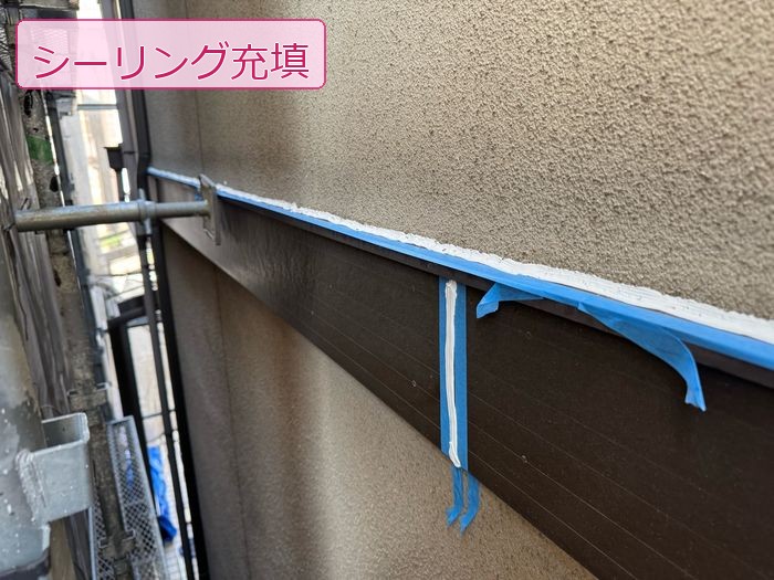 八尾市久宝寺のI様邸 外壁水切り部に白いシーリング材を増し打ちしている様子 青いマスキングテープで養生済み