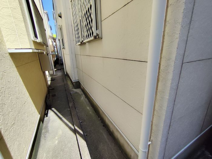 八尾市久宝寺のJ様邸 建物側面の狭い通路の現状 サイディング外壁と雨樋が確認できる