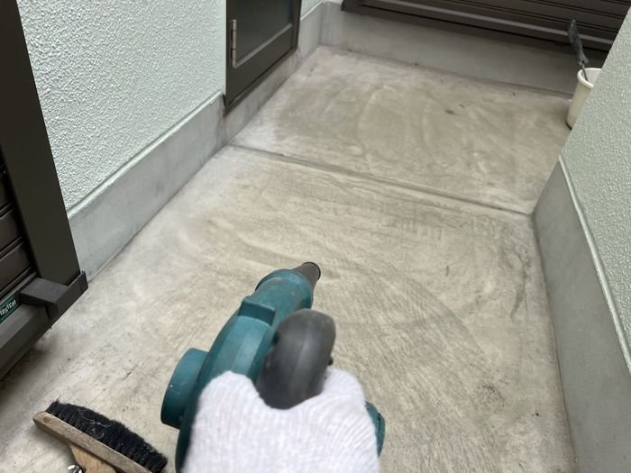 八尾市I様邸 ブロワーでベランダ床面のホコリやゴミを吹き飛ばしている様子