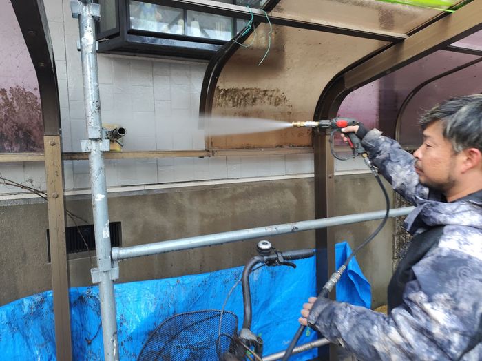 平野区喜連のアパート ガレージ内のタイル壁面を高圧洗浄機で洗い流している職人の様子